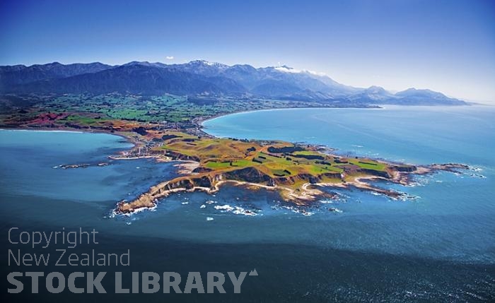 Aerial;Kaikoura;Kaikoura Peninsula;seaward Kaikoura Range;green fields;paddocks;brown hills;hills;mountains;ocean;pacific ocean;whale watch;seals;seal watch;blue sky;blue sea;rocky shoreline;Rail line;Station;rail Station;tourists