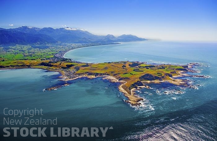 Aerial;Kaikoura;Kaikoura Peninsula;seaward Kaikoura Range;green fields;paddocks;brown hills;hills;mountains;ocean;pacific ocean;whale watch;seals;seal watch;blue sky;blue sea;rocky shoreline;Rail line;Station;rail Station;tourists