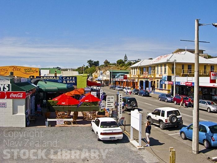 Kaikoura town Ctr;Kaikoura;Kaikoura Peninsula;seaward Kaikoura Range;green fields;paddocks;brown hills;hills;mountains;ocean;pacific ocean;whale watch;seals;seal watch;blue sky;blue sea;rocky shoreline;Rail line;Station;rail Station;tourists;Kaikoura;town Centre;cafes;hotel;red umbrellas;traffic